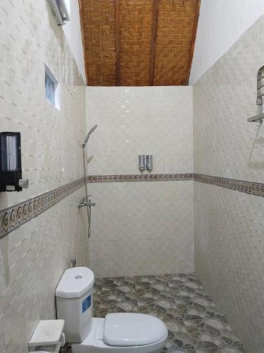 a bathroom with a toilet and a tv on the wall at Santhi Laba Bungalow in Nusa Penida