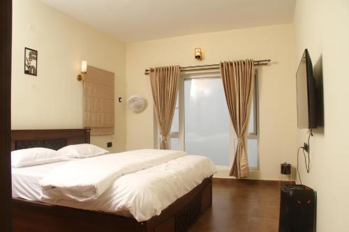 een slaapkamer met een bed, een televisie en een raam bij Luxurious Private Vantage Villa - Kotagiri in Kotagiri