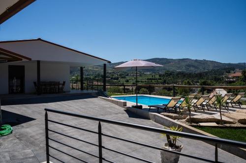 a patio with chairs and an umbrella and a swimming pool at Casa da Boucinha in Celorico de Basto