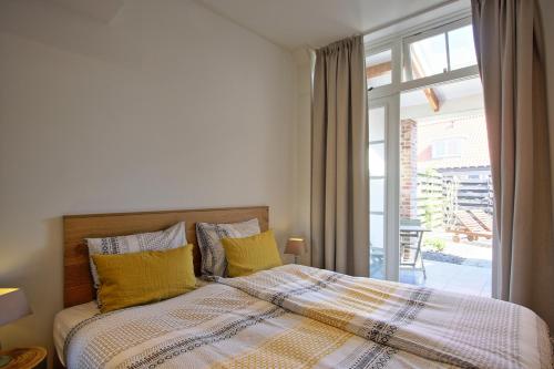 a bedroom with a bed with yellow pillows and a window at Studio Zuidstraat 3 - baddomburg in Domburg