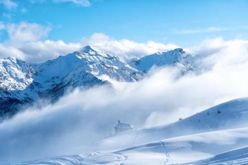 een met sneeuw bedekte berg met wolken ervoor bij Maison Soyeuse in Briançon