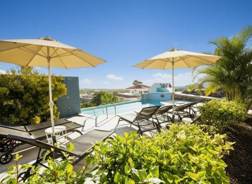 een terras met stoelen en parasols en een zwembad bij VillasRoyale Diamante in San Bartolomé