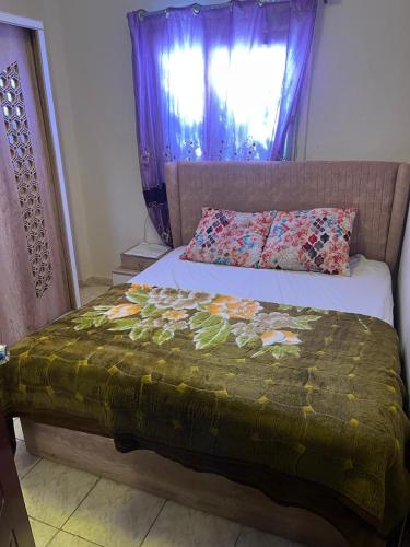 a bed with a green blanket and a window at Cozy Townhouse with a Backyard in Sheikh Zayed