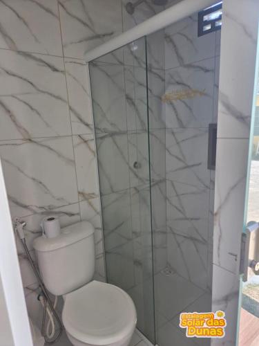 a bathroom with a toilet and a glass shower at Estalagem Solar das Dunas in Pirambu