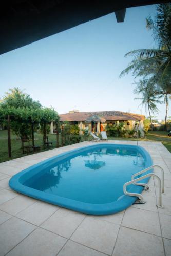 a blue swimming pool with a house in the background at Pousada Doromari in Taíba