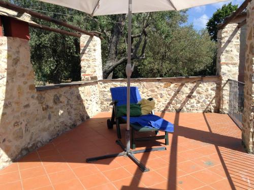 a blue chair under an umbrella on a patio at Case di Campo in Albenga