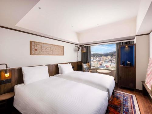a bedroom with a large white bed and a window at Mercure Hida Takayama in Takayama