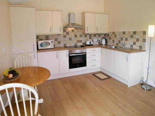 een keuken met witte kasten en een houten tafel bij Coombehayes Lodge in Uplyme