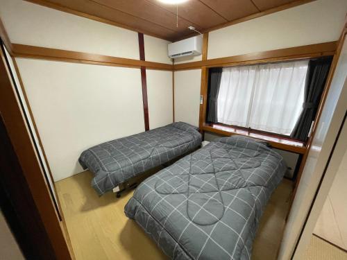 two beds in a small room with a window at Oharama House in Nasushiobara