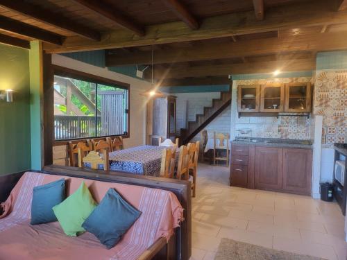 een woonkamer met een bank en een keuken bij Morada Sunset Vista Para o Mar in Praia do Rosa