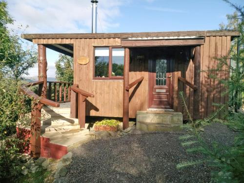 una baracca di legno con una porta e un portico di Glenkens Lodge a Dalry