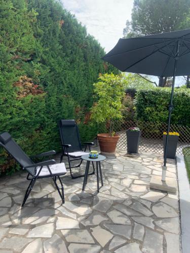 un patio avec deux chaises, une table et un parasol dans l'établissement Studio indépendant chez Pascale, à Saint-Clément-de-Rivière