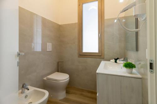 een badkamer met een toilet, een wastafel en een spiegel bij Affittacamere Lumal in Domus de Maria