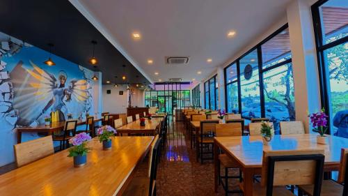 a restaurant with wooden tables and chairs and windows at Baan Phu Chalong Place in Ban Suan
