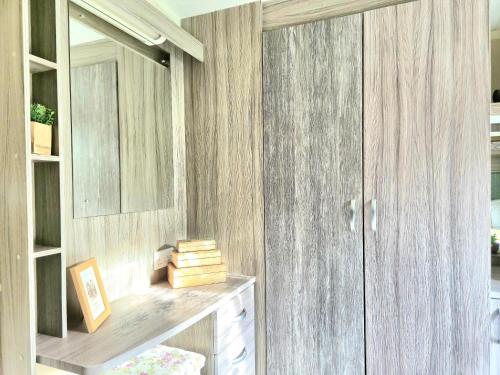 ein Zimmer mit Holzwänden und einem Schrank mit Schreibtisch in der Unterkunft Lovely Caravan With Decking At Cherry Tree Park Norfolk Ref 70724C in Belton