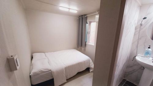 a small white room with a bed and a sink at 1971 Sinpung Inn in Seoul