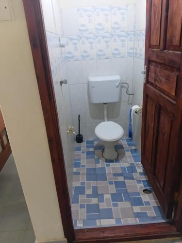 een badkamer met een toilet en een blauwe en witte tegelvloer bij Amatamata in Malindi