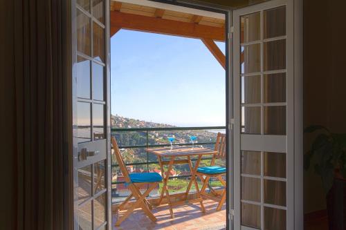 una puerta que da a un balcón con mesa y sillas en Orchid House Madeira, en Calheta