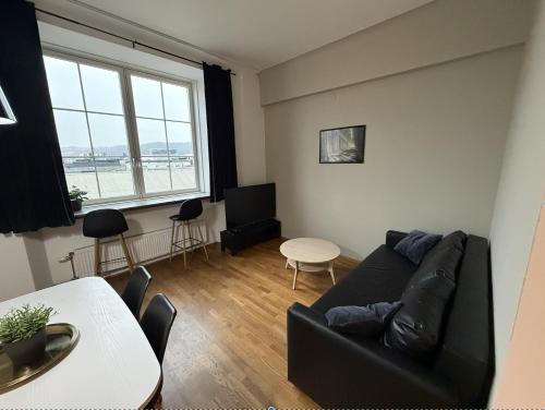 ein Wohnzimmer mit einer schwarzen Couch und einem Tisch in der Unterkunft Moderne og møblert 2-roms leilighet i hjertet av Oslo in Oslo