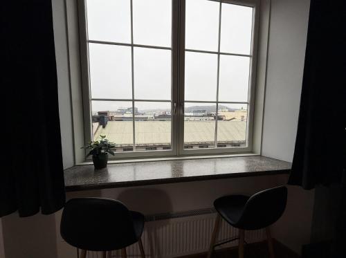 ein Fenster mit zwei Stühlen und Blick auf einen Flughafen in der Unterkunft Moderne og møblert 2-roms leilighet i hjertet av Oslo in Oslo