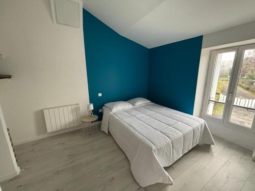 een slaapkamer met blauwe muren en een bed in een kamer bij Maison avec courette in Courlay