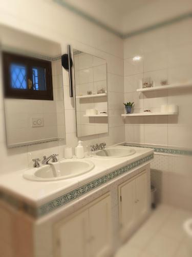 a white bathroom with two sinks and a mirror at B&B dei nonni in Maranello