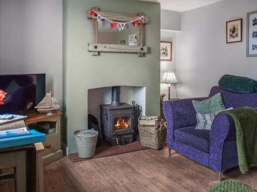 un soggiorno con camino e divano viola di Turning Tides Cottage a Scratby