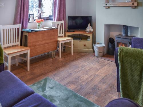 un soggiorno con TV, tavolo e sedie di Turning Tides Cottage a Scratby
