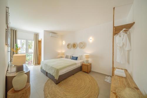 een witte slaapkamer met een bed en een tapijt bij Two Bedroom Beach Front Apartment with pool in Kiwengwa