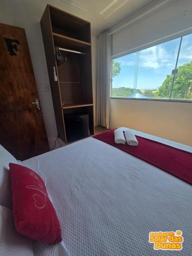 a bedroom with a large bed with red pillows and a window at Estalagem Solar das Dunas in Pirambu