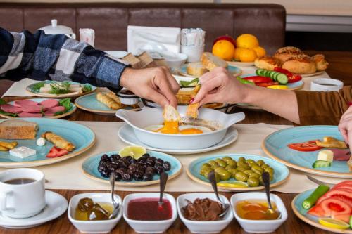 un tavolo pieno di piatti di cibo con persone che preparano il cibo di Grand Cali Hotel a Bozuyuk
