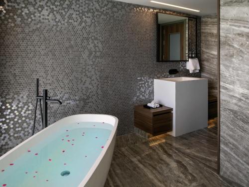un baño con bañera y lavabo en Mercure Larnaca Beach Resort, en Lárnaca