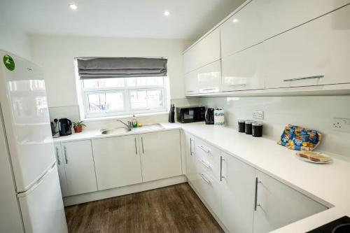 una cucina bianca con mobili bianchi e una finestra di Queens Court Ensuite Studio a Stoke on Trent