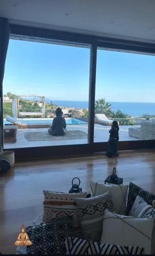 twee mensen zitten in een woonkamer en kijken uit over de oceaan bij Villa Ormalute in Pozzuoli