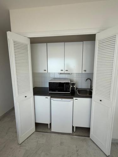 una piccola cucina con mobili bianchi e un forno a microonde di Eden Cap 2 a Cap d'Ail