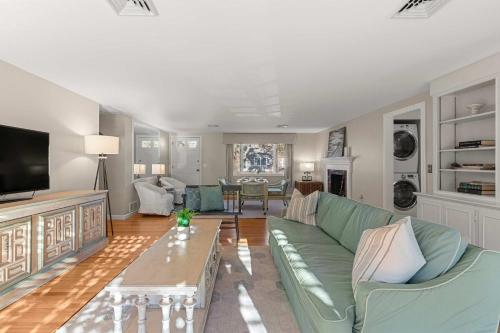 a living room with a green couch and a tv at Steps to Bayside Beach Central AC Large Backyard in Brewster