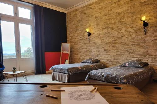 una camera con due letti e un muro di mattoni di Suite Baccara a Cluis