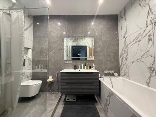 een badkamer met een wastafel, een bad en een toilet bij Kamanina Luxury Apartment in Odessa