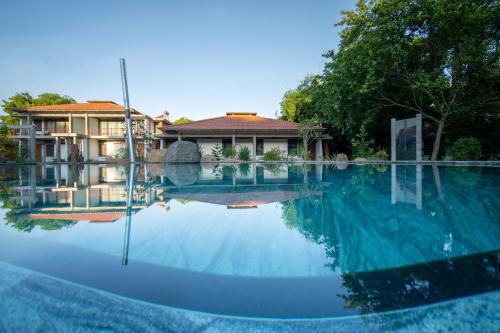 una grande piscina con una casa sullo sfondo di Sanctuary Amaidiyana - A CGH Earth Experience a Pondicherry