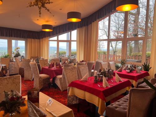 ein Esszimmer mit Tischen, Stühlen und Fenstern in der Unterkunft Hotel-Restaurant Weinberg in Artern