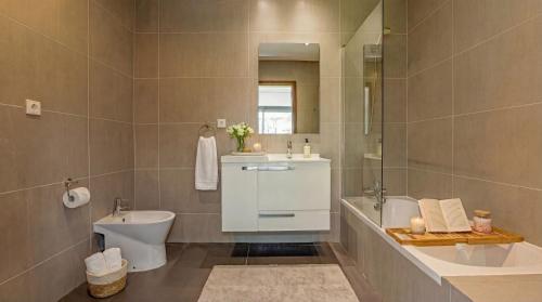 a bathroom with a sink and a toilet and a mirror at Cavalo Preto Ocean Breeze Apartment in Forte Novo Quarteira in Quarteira