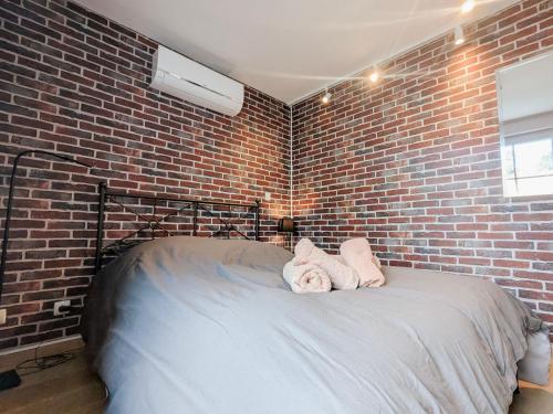 een slaapkamer met een bakstenen muur en een bed met handdoeken bij La Ressource, Claire in Fontguenand