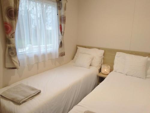 two beds in a small room with a window at Lovely new private caravan situated at park dean resorts ,st margerets at cliffe white cliffs kent in St Margarets at Cliff