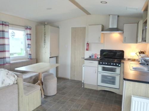 a kitchen with a table and a stove top oven at Lovely new private caravan situated at park dean resorts ,st margerets at cliffe white cliffs kent in St Margarets at Cliff