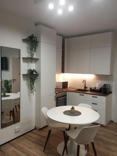 a white kitchen with a white table and chairs at RELAIS SUITE Modena Parc in Modena