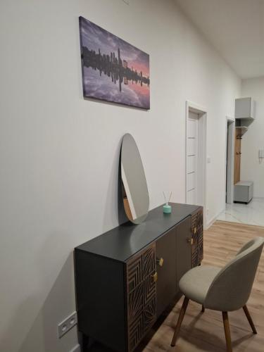 een dressoir met een spiegel en een stoel in een kamer bij Apartmán Central Point 1 in Humenné