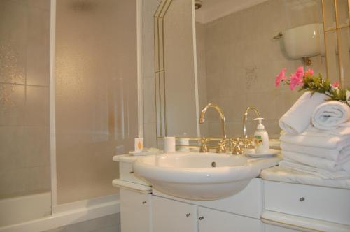 W białej łazience znajduje się umywalka i lustro. w obiekcie Casa del Bernini w mieście San Quirico dʼOrcia