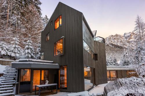 een huis met een zwarte gevel in de sneeuw bij Villa Jasna in Kranjska Gora