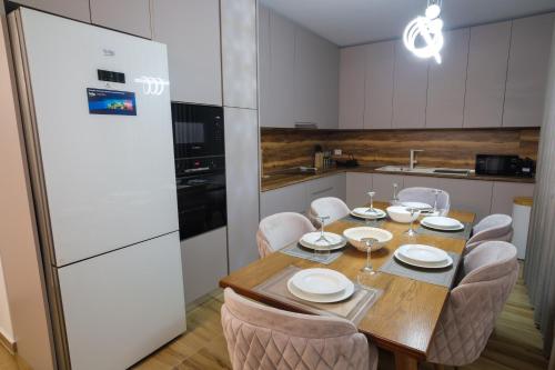 eine Küche mit einem Holztisch mit Stühlen und einem Kühlschrank in der Unterkunft The Grand Villa Babo in Vlorë