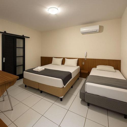 a bedroom with two beds and a table and a desk at Stallage Hotel in São Pedro